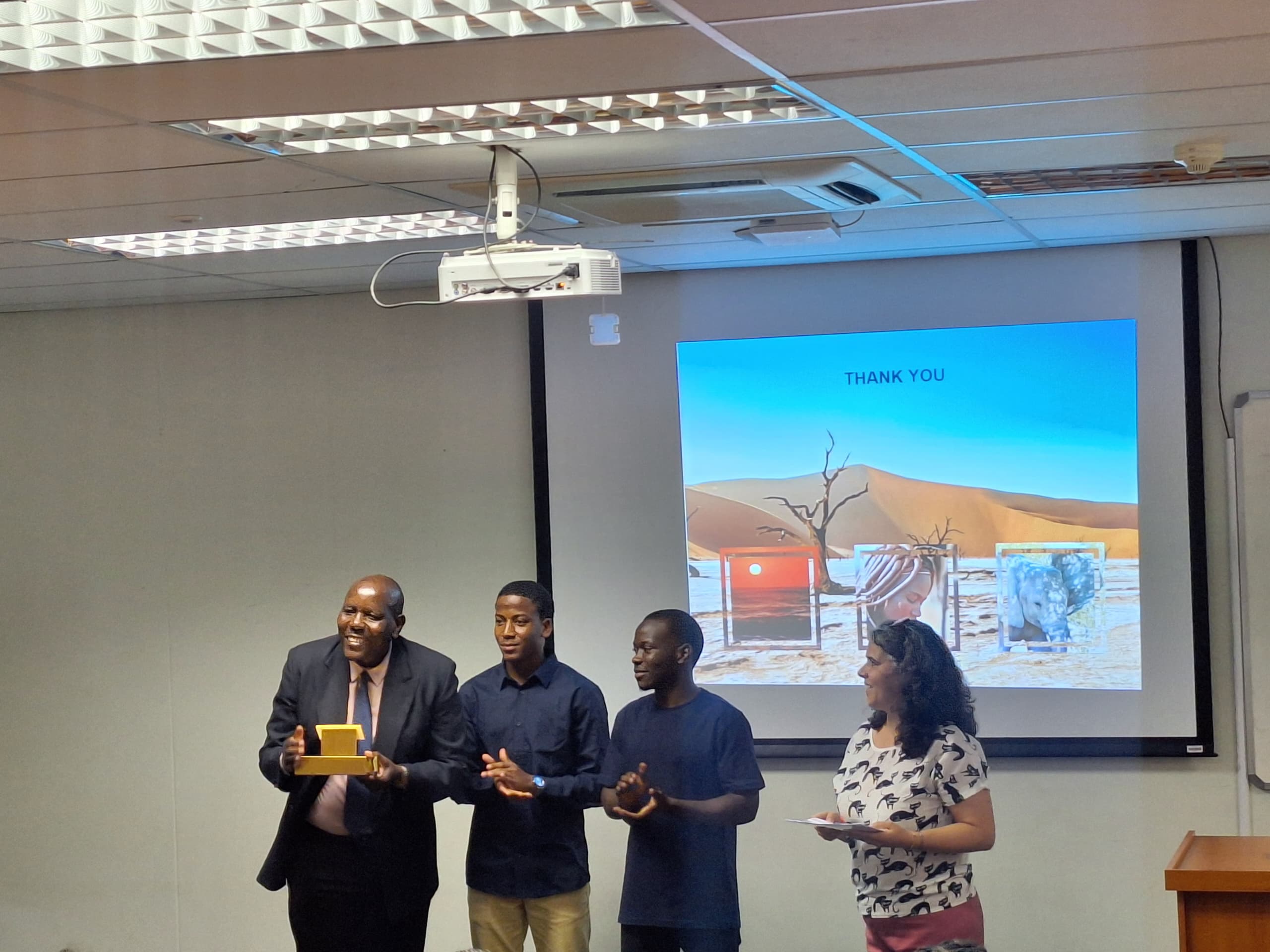 Professor  Andrew Niikondo, Deputy Vice Chancellor Teaching and Technology  receiving a gift  from the students from the National Institute of Petroleum, Kwanza Sul , Angola  while Ms Sandra Rocha, Engineer for Geology of Petroleum is looking on.